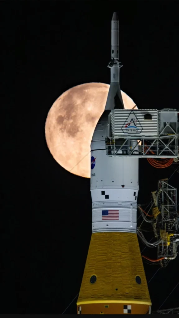 NASA Artemis II मिशन का रॉकेट, पीछे पूर्णिमा का चाँद दिखाई देता हुआ